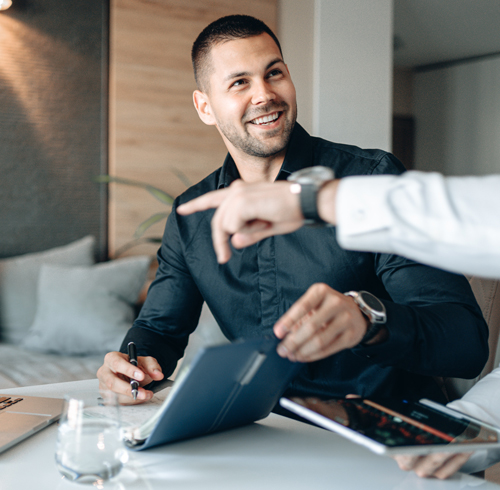 Man smiling in a meeting while taking notes