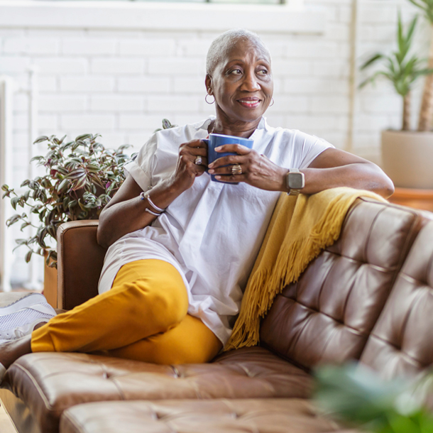 Woman drinking coffee on couch and looking out window